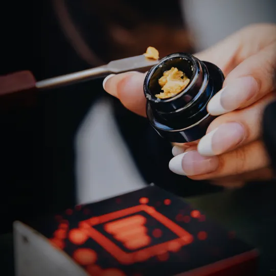 Hand holding cannabis concentrate container