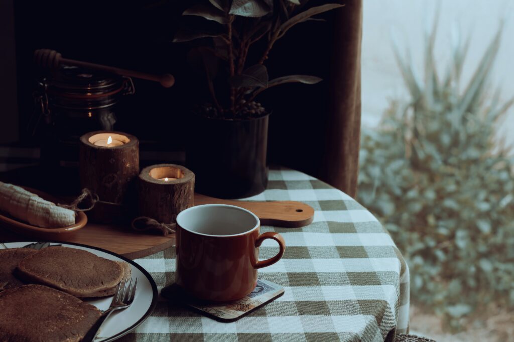 Pumpkin pancakes and a mug of cannabis infused pumpkin spice latte next to a window with autumn leaves.