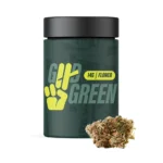 A dark green jar labeled “Good Green” with a yellow hand logo and text indicating 14 grams of cannabis flower. A cannabis bud is placed in front of the jar.