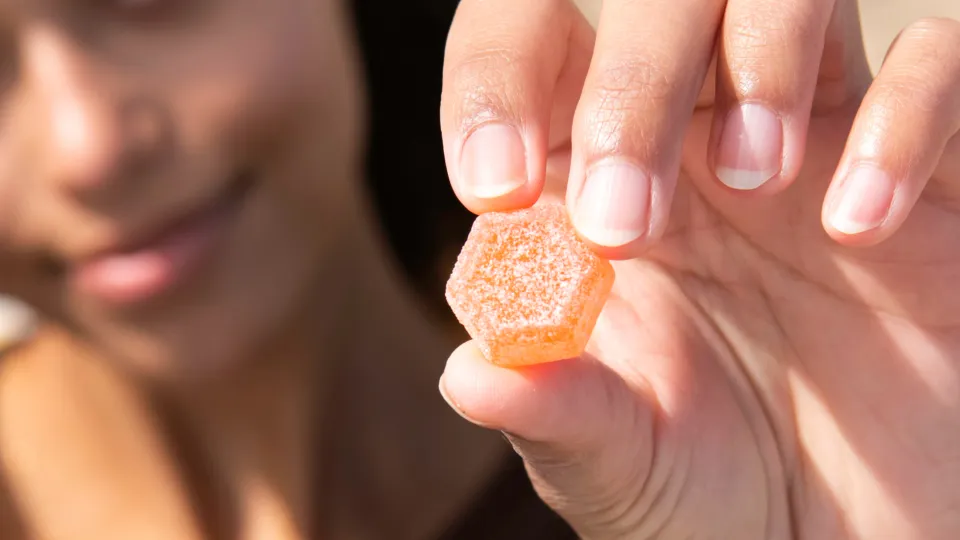 Skip the Smoke: Discreet Cannabis for Family Gatherings 3 Hand holding a medicated gummy candy.