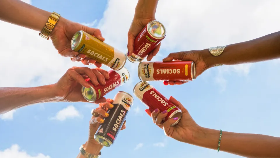 Skip the Smoke: Discreet Cannabis for Family Gatherings 4 Hands holding colorful beverage cans