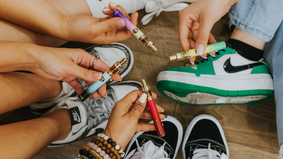 Hands holding colorful vape pens