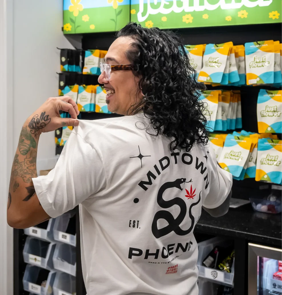 Story Cannabis team member wearing a Midtown Phoenix shirt in front of a cannabis display.